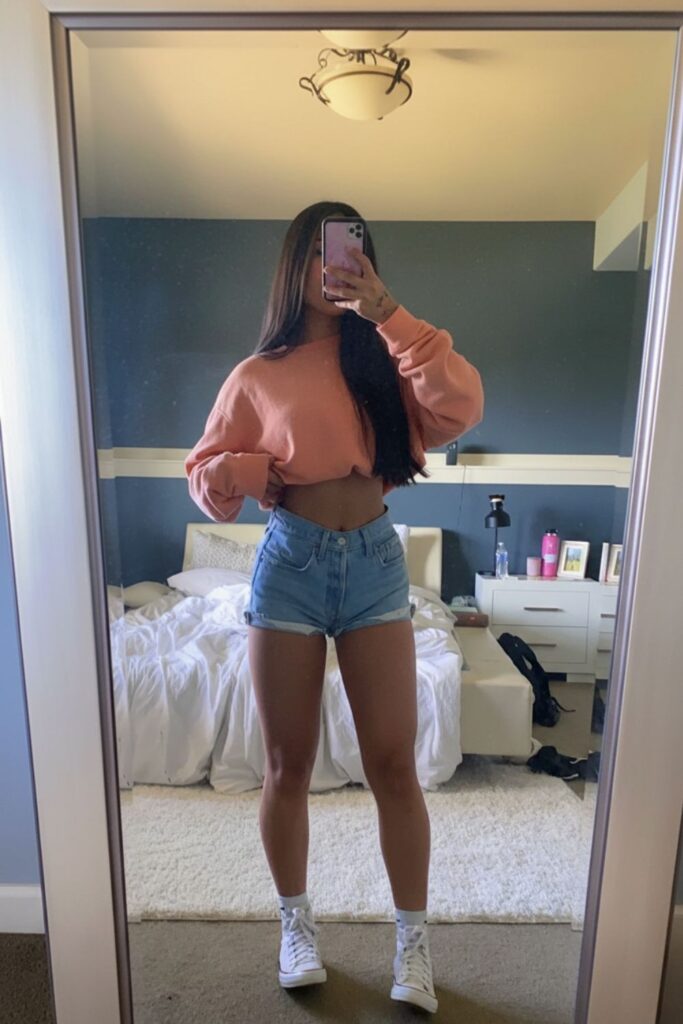 Mulher usando bermuda jeans de cintura alta com top listrado, para um look casual de verão.