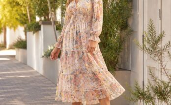 Mulher elegante usando vestido midi floral em tons pastel e botinhas brancas em ambiente externo com árvores ao fundo.