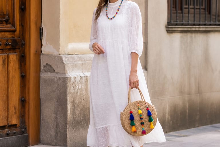 Mulher usando vestido branco transparente com acessórios coloridos em ambiente urbano, destacando detalhes das cores e estampas.