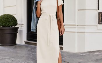 Mulher elegante vestindo vestido midi claro e tênis branco em ambiente urbano iluminado, com pose descontraída.