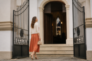 Mulher com vestido midi discreto e elegante caminhando em direcao a igreja classica iluminada